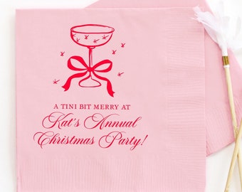 Puede incluir: Servilletas de cóctel rosas con un diseño de copa de martini roja y el texto "A Tini Bit Merry at Kat's Annual Christmas Party!" Dos agitadores de cóctel blancos y dorados también están en la imagen.
