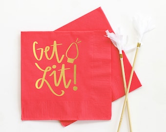 May include: Red paper napkins with gold lettering that reads "Get Lit!" and a lightbulb graphic. Two white and gold decorative sticks are also in the image. The napkins are square and have a textured surface.