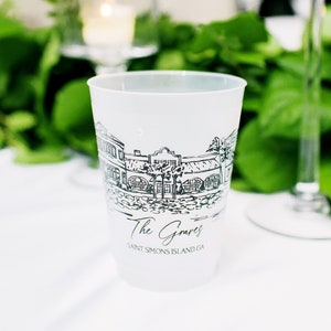 May include: A translucent white plastic cup featuring a black line drawing of a coastal building with palm trees. The text "The Graves" is printed in a script font above the text "SAINT SIMONS ISLAND, GA" in a simple sans-serif typeface.