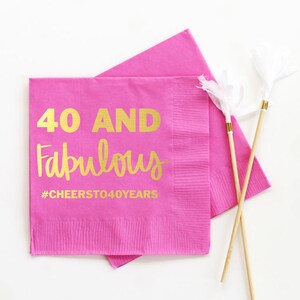 K&ouml;nnte beinhalten: Rosa Papier-Servietten mit goldener Aufschrift "40 and Fabulous #CHEERSTO40YEARS".
