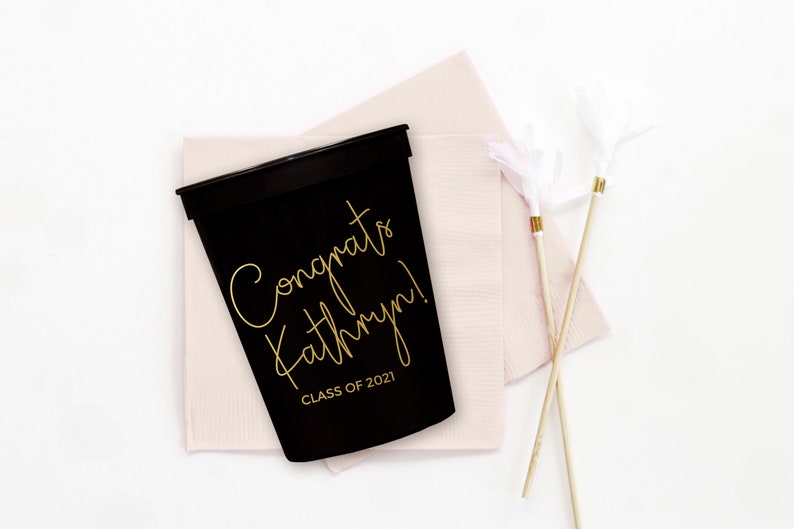 May include: Black plastic cup with gold lettering that says "Congrats Kathryn! Class of 2021".