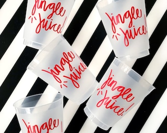 May include: A collection of frosted plastic cups with the words "Jingle Juice!" in red script. The cups are scattered on a black and white striped background, creating a festive and playful arrangement.