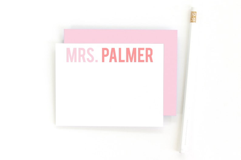 May include: A white card with a pink border and the text "MRS. PALMER" in pink and red lettering.