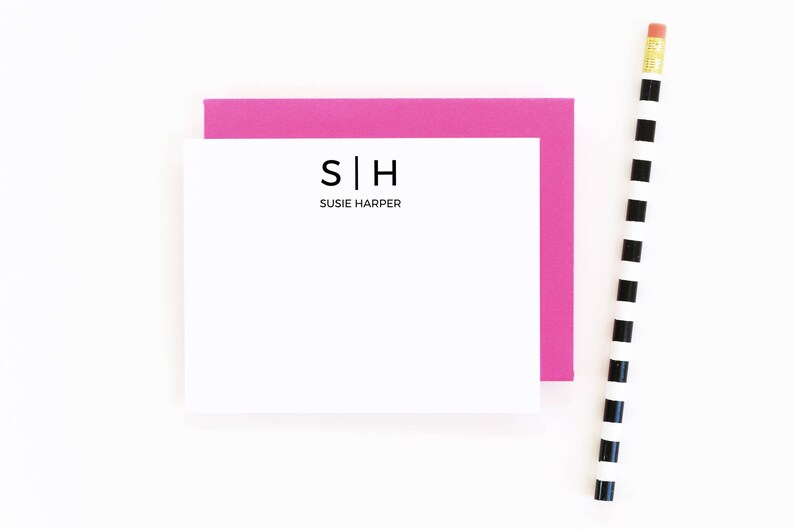 May include: A white card with a pink border. The card has a black monogram with the letters "S|H" and the text "Susie Harper" below the monogram.