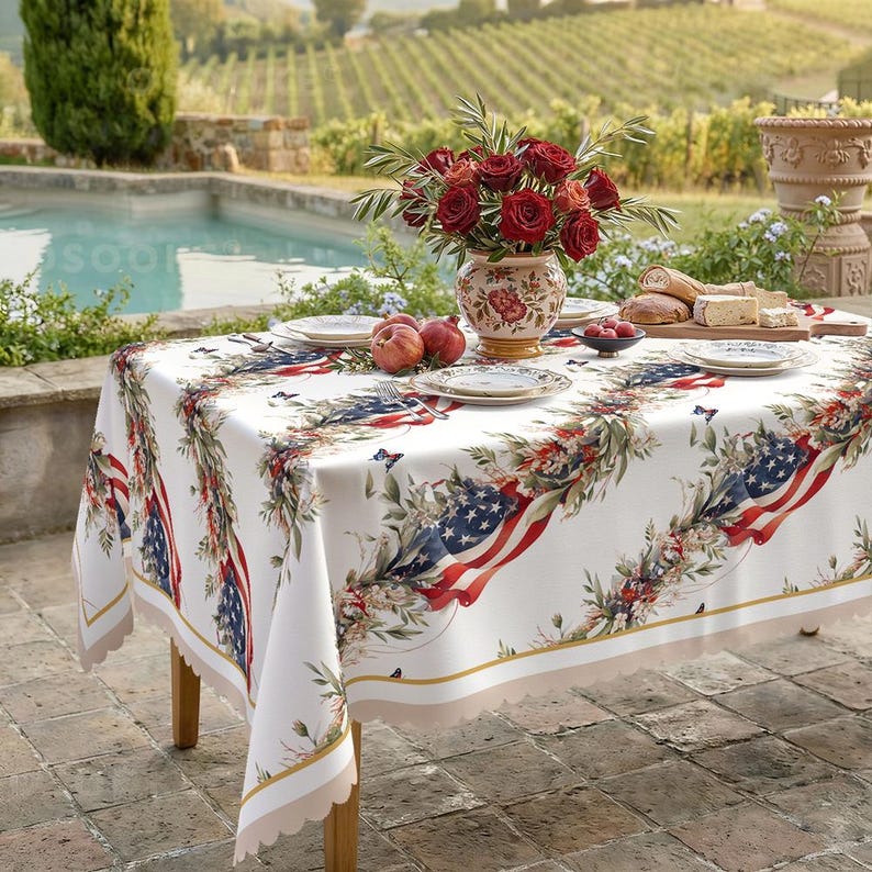 Pu&ograve; includere: Una tovaglia rettangolare con base bianca e un motivo ripetuto di bandiere americane, rose rosse, fogliame verde e piccole farfalle. I bordi sono rifiniti con un bordo smerlato in una tonalit&agrave; beige chiaro, creando un aspetto decorativo.