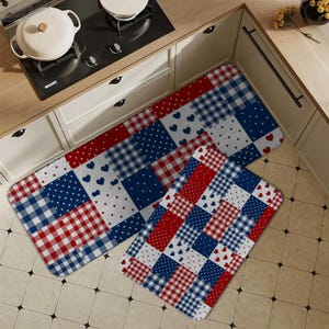 Può includere: Due tappeti da cucina con un design patchwork in rosso, bianco e blu. I tappeti presentano quadrati con pois, cuori e motivi a quadretti. Un tappeto è rettangolare, l'altro è più piccolo e di forma più quadrata.