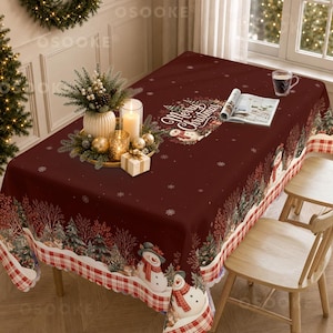 May include: A rectangular dark red tablecloth featuring a festive Christmas print with snowmen, pine trees, and snowflakes. The border displays a red and white plaid pattern. The text Merry Christmas is printed in white script on the top surface.