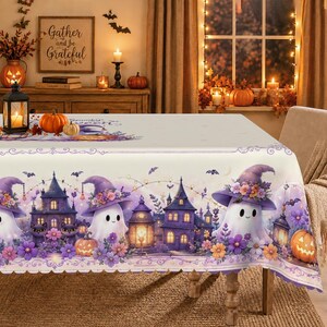 Op de afbeelding: Een rechthoekig tafelkleed met een Halloween-thema, voorzien van witte spoken met paarse bloemrijke heksenhoeden, donkerpaarse spookhuizen, oranje pompoenen en kleine vleermuizen. Het ontwerp bevat ook gloeiende lantaarns en paarse bloemen.