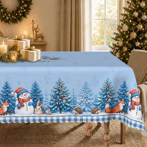 Peut inclure: Une nappe rectangulaire bleu clair ornée d'une scène hivernale répétitive avec des bonhommes de neige, des renards, des lapins, des hérissons et des sapins décorés. Le bord inférieur présente une bordure à carreaux bleu et blanc festonnée.