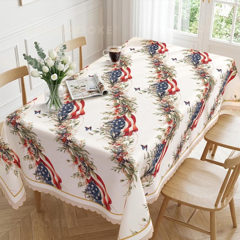 Pu&ograve; includere: Una tovaglia rettangolare con base bianca caratterizzata da un motivo verticale ripetuto di bandiere americane drappeggiate con fogliame verde, bacche rosse e piccole farfalle blu. I bordi del tessuto presentano una finitura smerlata dorata.