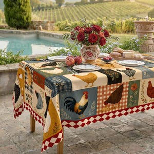 Puede incluir: Un mantel rectangular con un diseño de patchwork de varios pollos, gallos y motivos florales en tonos rojos, amarillos, azules y negros. El borde muestra un patrón de diamantes rojos y blancos, cubriendo una mesa puesta con platos.