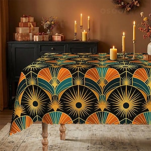 May include: A rectangular tablecloth featuring a repeating geometric pattern of black, orange, and teal fan-shaped motifs with radiating yellow sunburst lines. The fabric drapes over a table, displaying a bold, symmetrical design across its surface.
