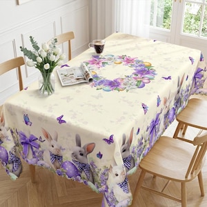 May include: Cream Easter tablecloth with a repeating pattern of bunnies, purple bows, and Easter eggs. The border features bunnies with blue and white checkered bow ties. A floral wreath and butterflies decorate the center.
