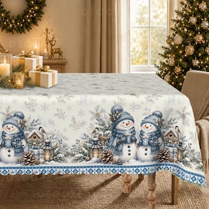 May include: A rectangular tablecloth featuring a repeating winter scene with snowmen wearing blue hats and scarves, pine branches, pinecones, lanterns, and birdhouses on a cream background with a blue and white geometric border pattern.
