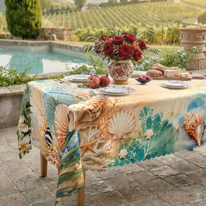 May include: A rectangular tablecloth featuring a vibrant print of seashells, coral, starfish, and tropical flowers in shades of blue, orange, and white. The design includes illustrations of a small fish and various marine life patterns on a light background.