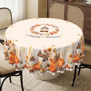Könnte beinhalten: Eine runde Tischdecke mit cremefarbenem Hintergrund, die einen zentralen Kranz aus Herbstblättern und einen Vogelkäfig mit dem Text Happy Autumn zeigt. Der Rand ist mit Kürbissen, Sonnenblumen, Weizen, Tannenzapfen und Laternen bedruckt.