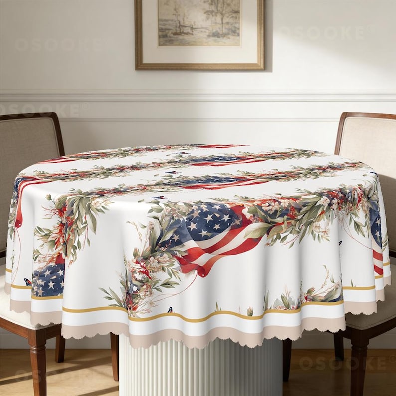 Pu&ograve; includere: Una tovaglia rotonda con sfondo bianco caratterizzata da un motivo ripetuto di bandiere americane drappeggiate, intrecciate con ghirlande di foglie verdi e piccoli fiori bianchi. La tovaglia presenta un bordo smerlato e una linea dorata.
