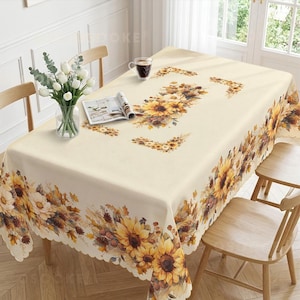 May include: A rectangular tablecloth with a cream-coloured base featuring a vibrant sunflower and autumn foliage print. The design includes a central floral arrangement, corner accents, and a scalloped edge border filled with sunflowers and pinecones.