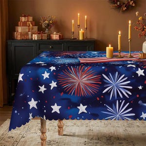 May include: A rectangular tablecloth featuring a deep blue background with a repeating pattern of white stars and red and white firework bursts. The design includes a section resembling the American flag with red and white stripes.