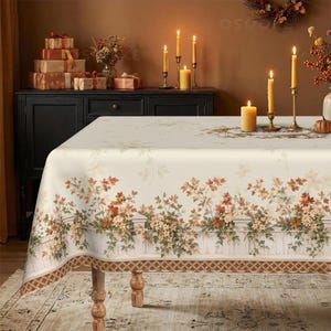 May include: A rectangular tablecloth featuring a cream-colored base with a printed design of a white picket fence adorned with autumn leaves in shades of orange, brown, and green, finished with a brown lattice-patterned border along the bottom edge.