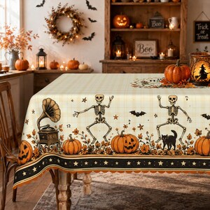 May include: A rectangular tablecloth featuring a cream-coloured plaid pattern with a Halloween-themed border. The design includes dancing skeletons, orange pumpkins, a vintage gramophone, a black cat, bats, and stars, finished with a scalloped edge.