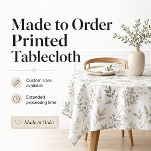 Könnte beinhalten: Eine runde Tischdecke mit weißem Untergrund und einem botanischen Druck aus grünen und braunen Blättern sowie kleinen Blüten. Der Text lautet Made to Order Printed Tablecloth, Custom sizes available, Extended processing time und Made to Order.