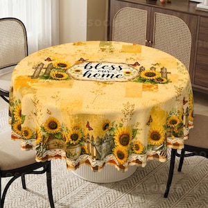 Könnte beinhalten: Eine runde Tischdecke mit gelbem Hintergrund, verziert mit Sonnenblumen, Schmetterlingen und Holzzaunmotiven. In der Mitte steht der Schriftzug "bless our home" in schwarzer Schreibschrift. Die Ränder sind mit weißer Spitze verziert.