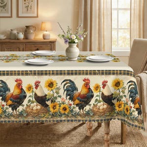 May include: A rectangular tablecloth featuring a repeating pattern of roosters, sunflowers, and nests with eggs. The design includes a dark blue and yellow plaid border along the edges. The fabric is cream-colored with a detailed, colorful print.