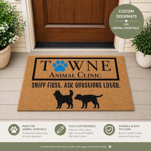 May include: A rectangular tan coir doormat featuring a black border, the text "TOWNE ANIMAL CLINIC" with a blue paw print replacing the letter O, and the text "SNIFF FIRST. ASK QUESTIONS LATER." above two black silhouettes of dogs.
