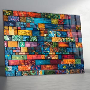May include: A colorful, abstract wall art piece featuring a mosaic of rectangular blocks. The blocks are painted in a variety of colors including blue, orange, green, and red, with floral and geometric patterns. The artwork has a glossy finish.