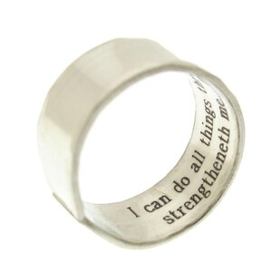 May include: A silver ring with a wide band and a quote inscribed on the inside: "I can do all things through Christ who strengtheneth me."