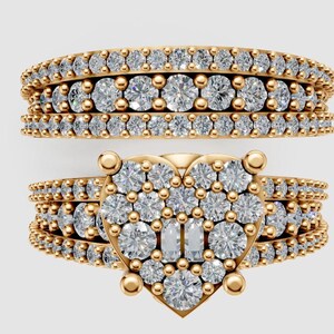 Puede incluir: Dos anillos de oro con piedras preciosas transparentes. Un anillo es una banda con tres filas de piedras preciosas. El otro anillo tiene un diseño en forma de corazón con piedras preciosas y una banda con piedras preciosas.