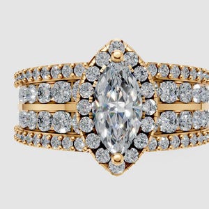 May include: A gold ring featuring a central marquise-cut diamond, encircled by smaller diamonds. The ring has multiple bands of smaller diamonds, creating a layered design. The ring is set against a light background.