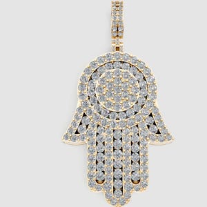 May include: A gold-colored Hamsa hand pendant encrusted with numerous small, sparkling clear gemstones. The pendant features a detailed design with a loop at the top for a chain. The hand-shaped charm is a symbol of protection.