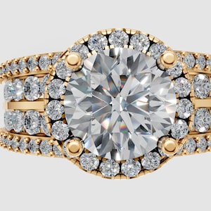 Puede incluir: Un anillo de compromiso de oro con una gran piedra central de diamante transparente y redondo. El anillo presenta un halo de diamantes más pequeños alrededor de la piedra central y a lo largo de la banda. La banda tiene tres filas de diamantes.