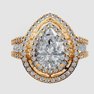 Op de afbeelding: Een gouden ring met een peervormige diamant als middensteen, omringd door een halo van kleinere diamanten. Extra diamanten sieren de band, wat een sprankelend effect creëert. De ring staat tegen een neutrale achtergrond.