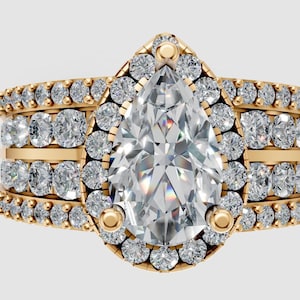 Könnte beinhalten: Ein goldener Verlobungsring mit einem birnenförmigen Diamanten als Mittelstein, umgeben von einem Halo aus kleineren Diamanten. Das Band hat drei Reihen runder Diamanten. Ein luxuriöses Schmuckstück.