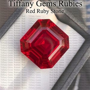 May include: A faceted, vibrant red ruby gemstone, presented in a dark gray jewelry box. The stone is a deep crimson color, with a geometric cut that reflects light. Text on the image reads "Tiffany Gems Rubies" and "Red Ruby Stone."