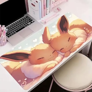 May include: A rectangular desk mat with a cartoon illustration of two Eevee characters cuddling. The mat has a light blue background with white hearts. The Eevee characters are in shades of orange and brown.