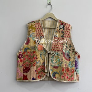 May include: A sleeveless vest featuring a patchwork design with various floral and geometric patterns in shades of yellow, red, blue, and green. The garment has a front tie closure, a striped interior lining, and the text TheFabricCharm.