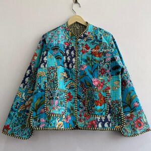 Puede incluir: Una chaqueta acolchada con un diseño de patchwork vibrante en tonos turquesa, azul y rosa con estampados florales y de cachemira. La prenda tiene cuello redondo, mangas largas, dos bolsillos delanteros y un borde a rayas. El texto dice TheFabricCharm.