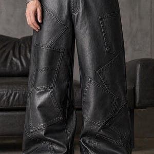 May include: Black leather pants with a patchwork design. The pants have a wide leg and multiple pockets. The stitching is visible, and the pants appear to be made of a durable material. The pants are worn with black shoes.