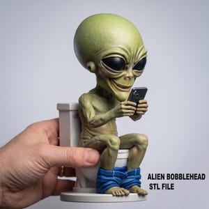 Pode incluir: Uma figura de alienígena verde com cabeça oscilante sentada numa sanita, segurando um smartphone. O alienígena tem olhos grandes e pretos e usa calças de ganga azuis. O texto "ALIEN BOBBLEHEAD STL FILE" é visível.