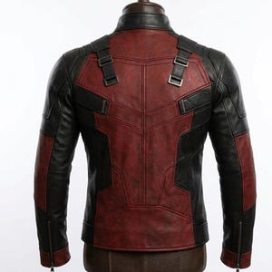 May include: A black and red leather jacket with a stand-up collar and zipper sleeves. The back of the jacket features a red panel design with black accents and adjustable straps. The jacket is displayed on a mannequin.