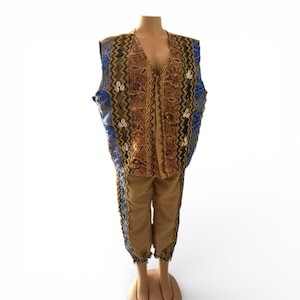 Puede incluir: Un conjunto de dos piezas color beige sobre un maniquí. El chaleco es marrón con detalles azules y dorados, y los pantalones son beige con ribetes azules. El chaleco tiene cuello en V y está abotonado. El conjunto es probablemente vintage o étnico.
