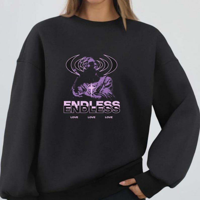 May include: Black sweatshirt featuring a purple graphic of a figure with radiating lines and a cross. The word "ENDLESS" is stacked above three instances of the word "LOVE" in a white sans-serif font. A casual, comfortable style.