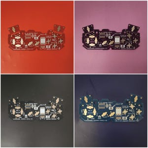 Pode incluir: Quatro placas de circuito preto com componentes eletrônicos dourados, incluindo botões e chips. Cada placa tem uma cor de fundo diferente: vermelho, rosa, preto e azul. O texto é visível em cada placa.
