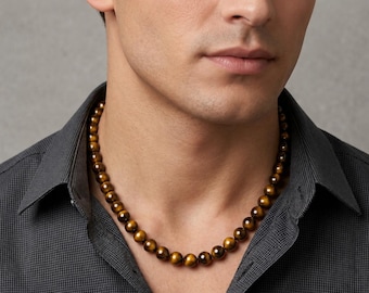 May include: A beaded necklace with golden-brown tiger eye stones. The necklace is worn around the neck, and the beads are evenly sized and round. The necklace is a jewelry item.