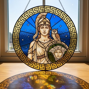 May include: A round stained glass panel depicting a classical female figure with an owl and a shield. The artwork features a blue background with stars, gold accents, and a decorative border. The panel is hanging from a chain.