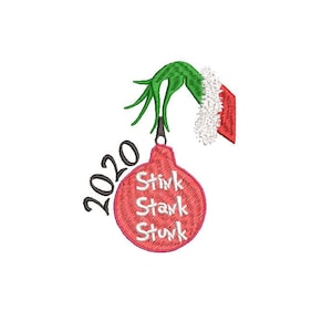 Puede incluir: Un adorno navideño rojo con las palabras "Stink Stark Stunk" y el año "2020" escrito en él. Una mano verde del Grinch con un gorro de Papá Noel rojo sostiene el adorno.
